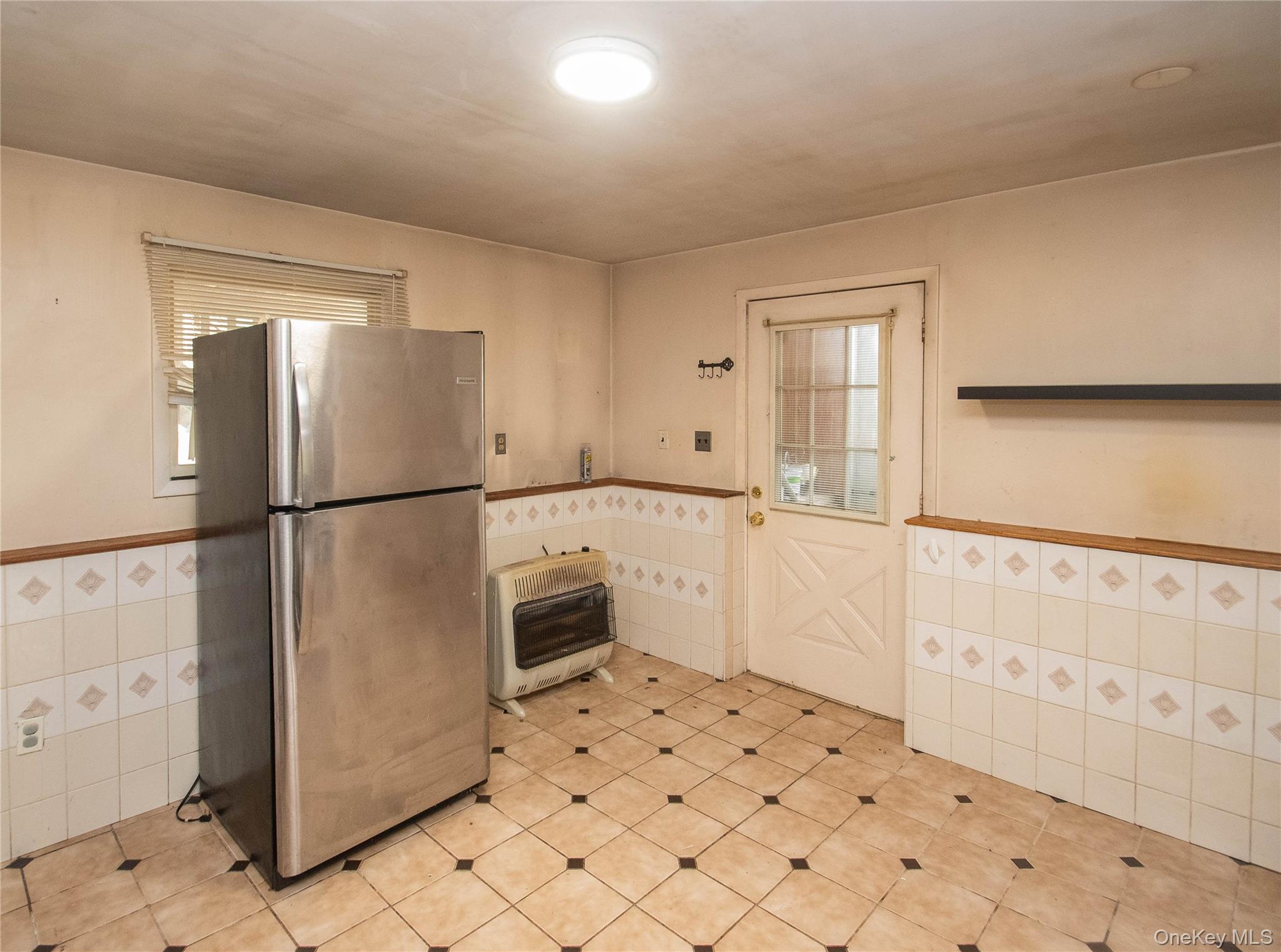 20 Valley Road Forestburgh, NY 12777 - Photo 27 of 38 Kitchen with tile walls, wainscoting, freestanding refrigerator, heating unit, and light tile patterned floors