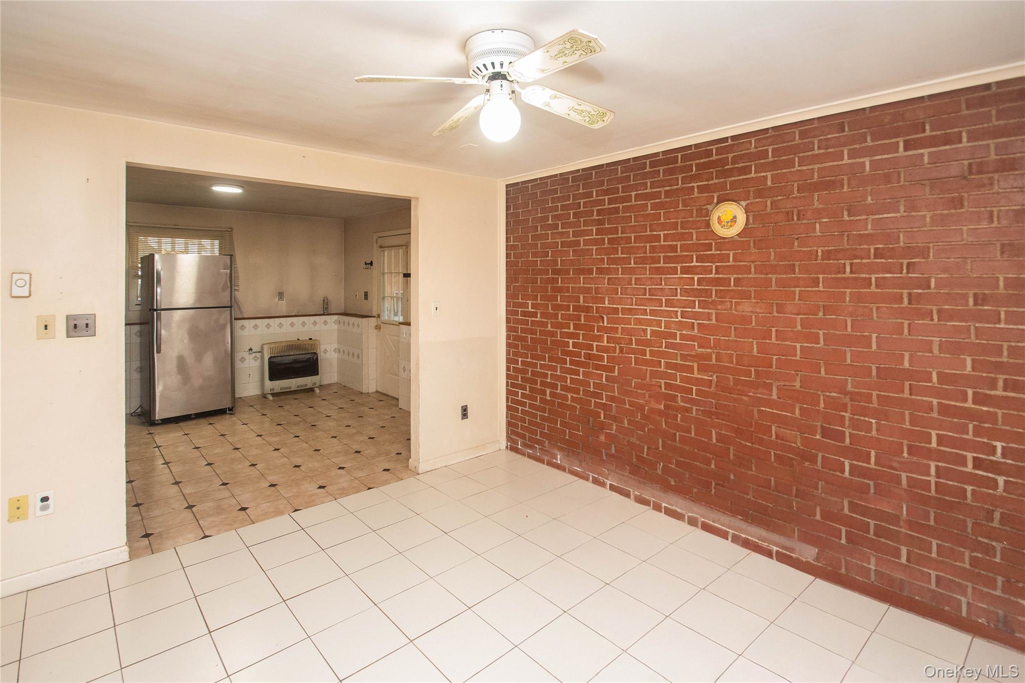 20 Valley Road Forestburgh, NY 12777 - Photo 29 of 38 Empty room featuring brick wall, heating unit, ceiling fan, and light tile patterned flooring