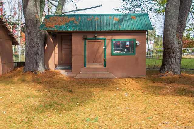 a view of yellow house with a big yard and large tree