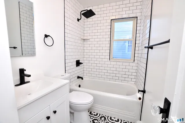 a bathroom with a sink a toilet a mirror and shower