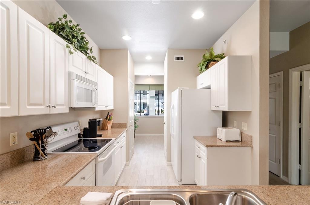 7920 Mahogany Run Lane, Unit 1011 Naples, FL 34113 - Photo 4 of 22 a kitchen with stainless steel appliances kitchen island granite countertop a refrigerator a sink dishwasher and white cabinets with wooden floor