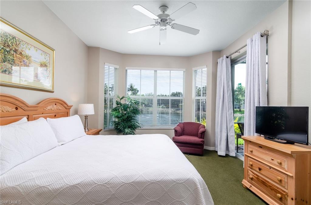 7920 Mahogany Run Lane, Unit 1011 Naples, FL 34113 - Photo 5 of 22 a bedroom with a bed flat screen tv and a window