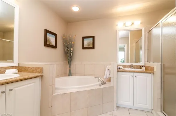 a bathroom with a granite countertop tub sink and mirror