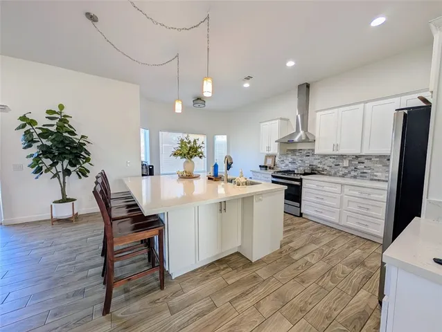 a kitchen with stainless steel appliances kitchen island granite countertop a table chairs in it and wooden floors