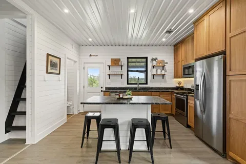 a kitchen with stainless steel appliances a dining table chairs refrigerator and sink