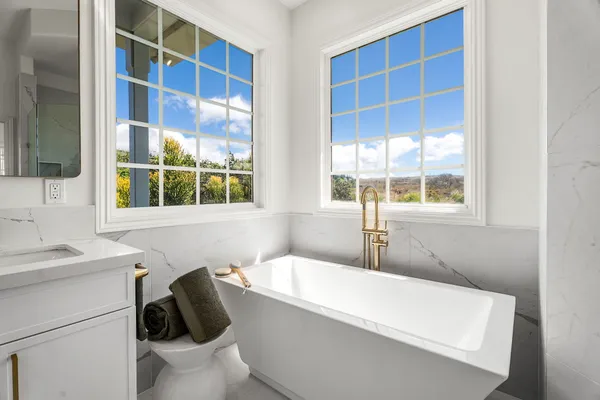 a bathroom with a sink a toilet a window and mirror
