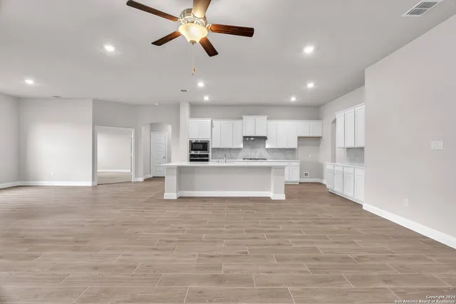 a view of kitchen with kitchen island stainless steel appliances cabinets a sink and a counter top space