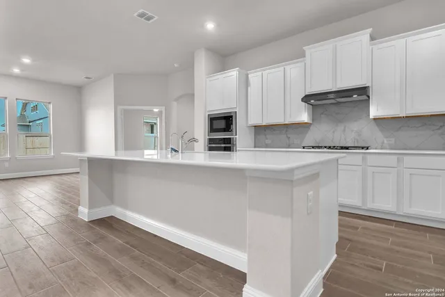 a kitchen with granite countertop white cabinets and stainless steel appliances