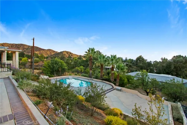 an aerial view of a house with swimming pool and large trees