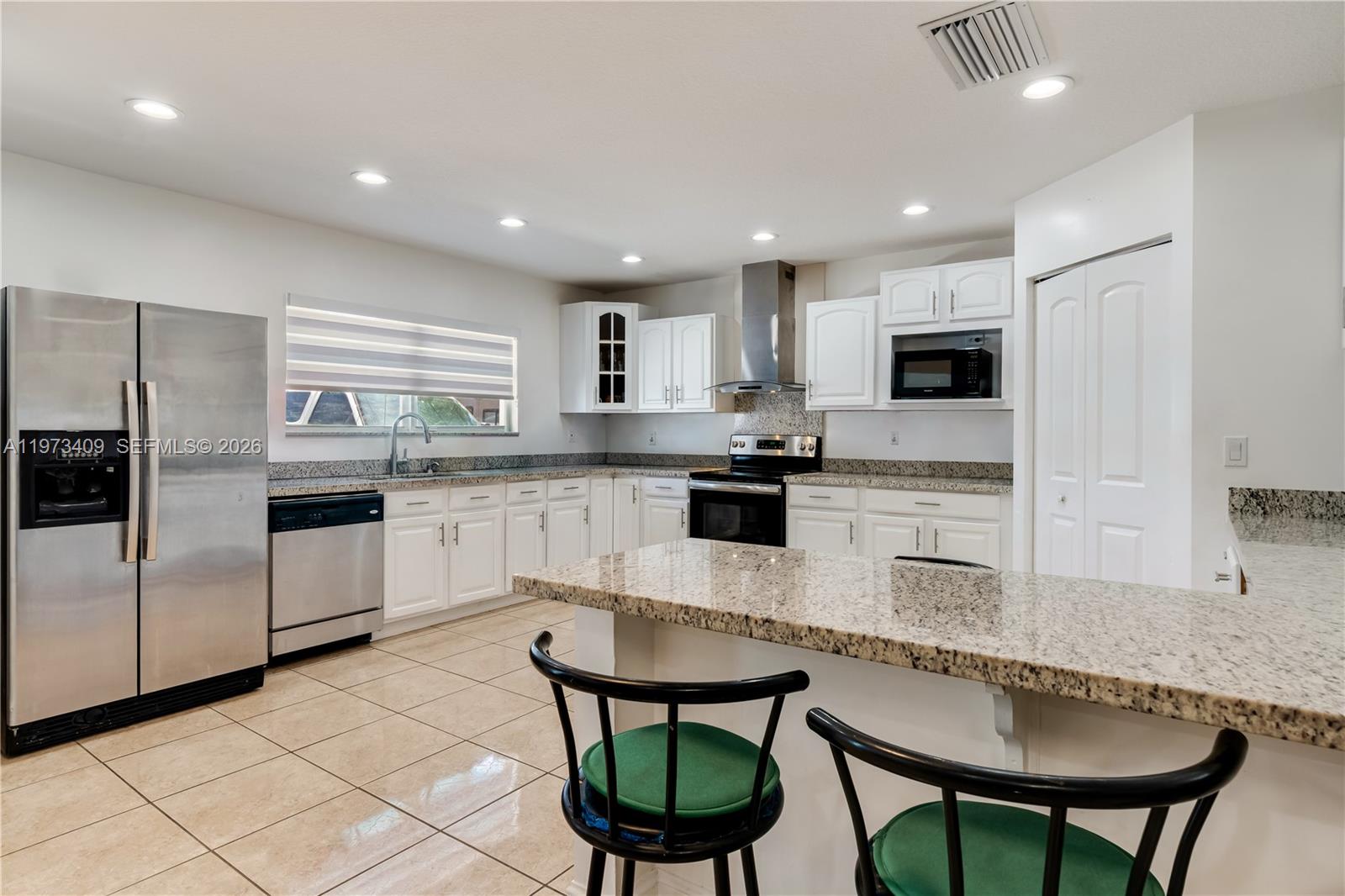 13050 Southwest 26th Street Miami, FL 33175 - Photo 22 of 43 a kitchen with stainless steel appliances granite countertop a stove a sink a refrigerator a microwave and white cabinets