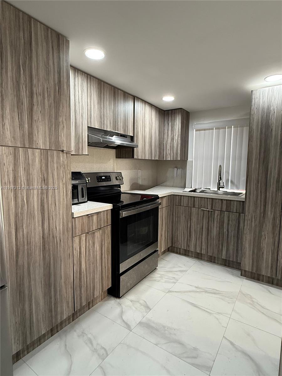 4850 Southwest 63rd Terrace, Unit 312 Davie, FL 33314 - Photo 3 of 27 a kitchen with stainless steel appliances granite countertop a stove a sink and a refrigerator