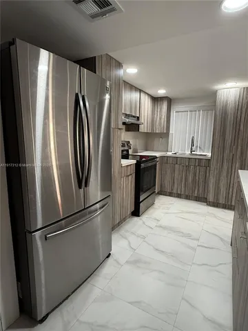 a metallic refrigerator freezer sitting inside of a kitchen