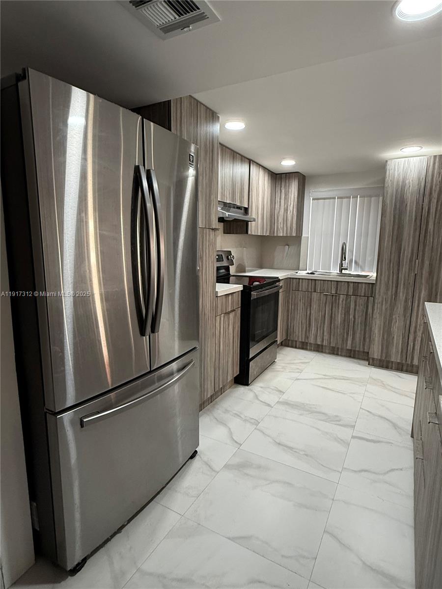 4850 Southwest 63rd Terrace, Unit 312 Davie, FL 33314 - Photo 4 of 27 a metallic refrigerator freezer sitting inside of a kitchen