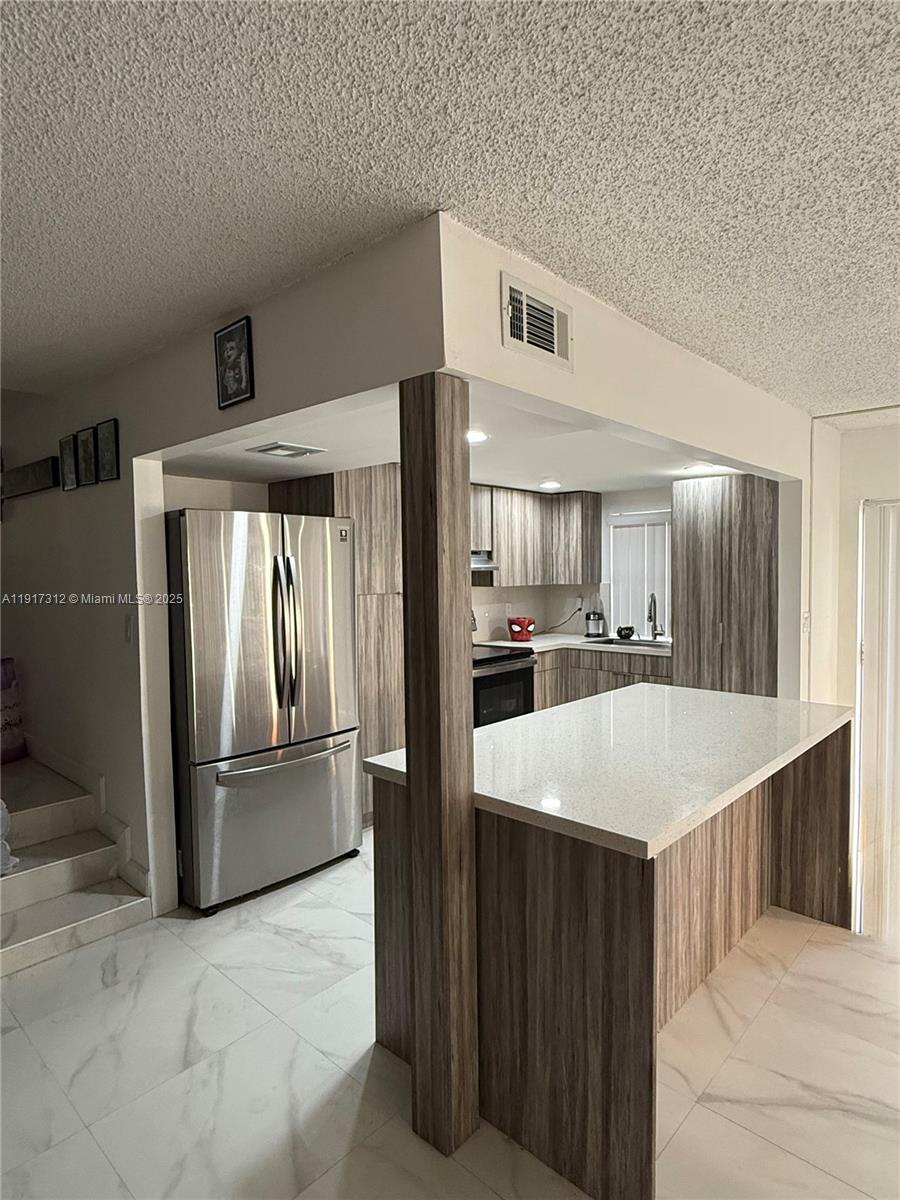 4850 Southwest 63rd Terrace, Unit 312 Davie, FL 33314 - Photo 6 of 27 a large kitchen with a refrigerator a stove and cabinets