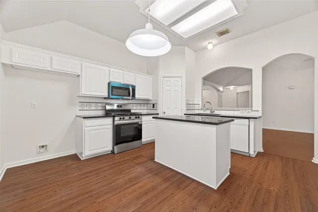 a kitchen with granite countertop white cabinets and stainless steel appliances