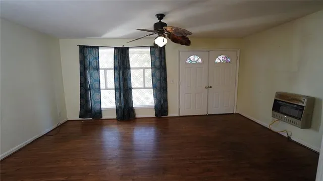 a view of an empty room with a window and wooden floor