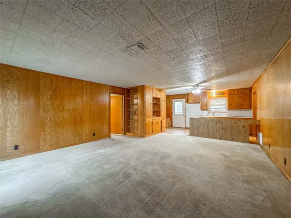 an empty room with a chandelier fan and windows