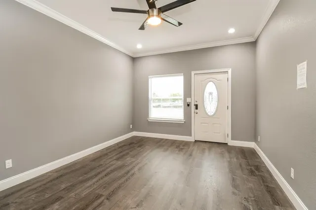 an empty room with wooden floor mirror and windows