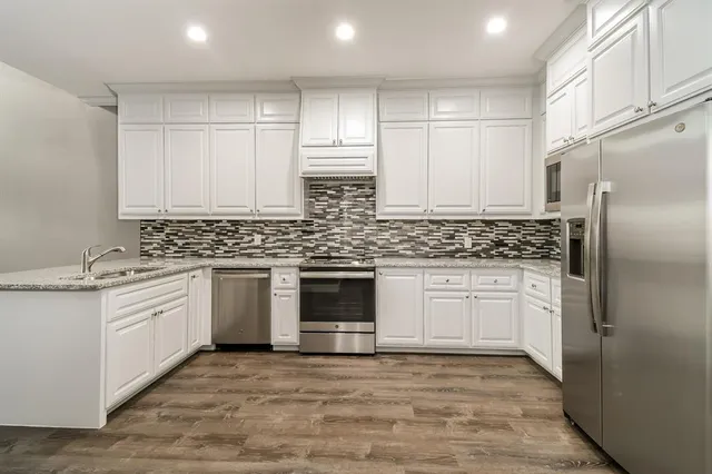 a kitchen with granite countertop white cabinets and white stainless steel appliances