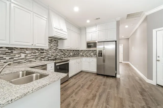 a kitchen with granite countertop a refrigerator sink and cabinets
