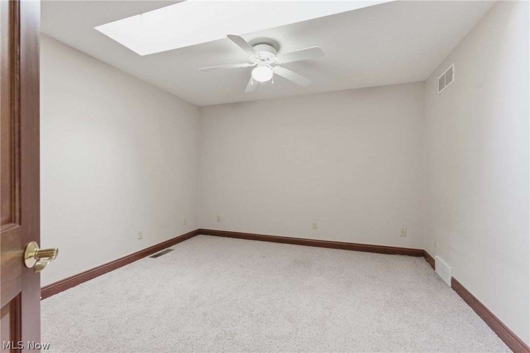 2184 Brenner Road Northeast Carrollton, OH 44615 - Photo 22 of 50 Neutral-toned interior room featuring a skylight, ceiling fan, and light-colored carpeting