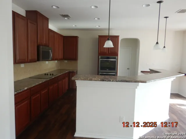 a kitchen with stainless steel appliances granite countertop a sink and a refrigerator