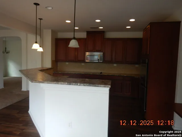 a kitchen with kitchen island granite countertop wooden cabinets and a granite counter tops