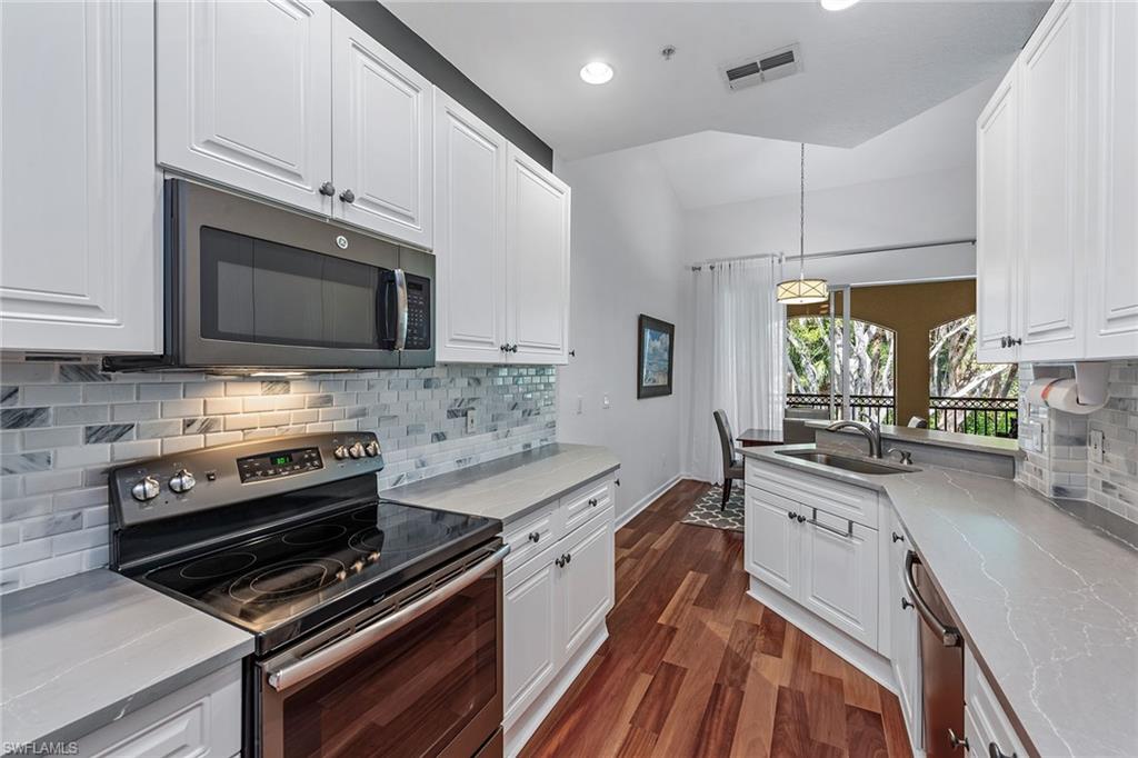 3945 Deer Crossing Court, Unit 203 Naples, FL 34114 - Photo 8 of 50 a kitchen with stainless steel appliances a stove microwave and cabinets