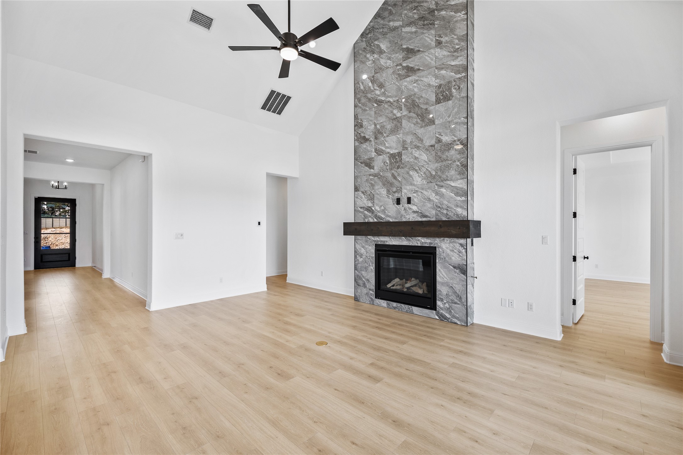 3213 Lookout Mountain Road Georgetown, TX 78628 - Photo 10 of 40 Unfurnished living room with a premium fireplace, a ceiling fan, light wood-style floors, and lofted ceiling