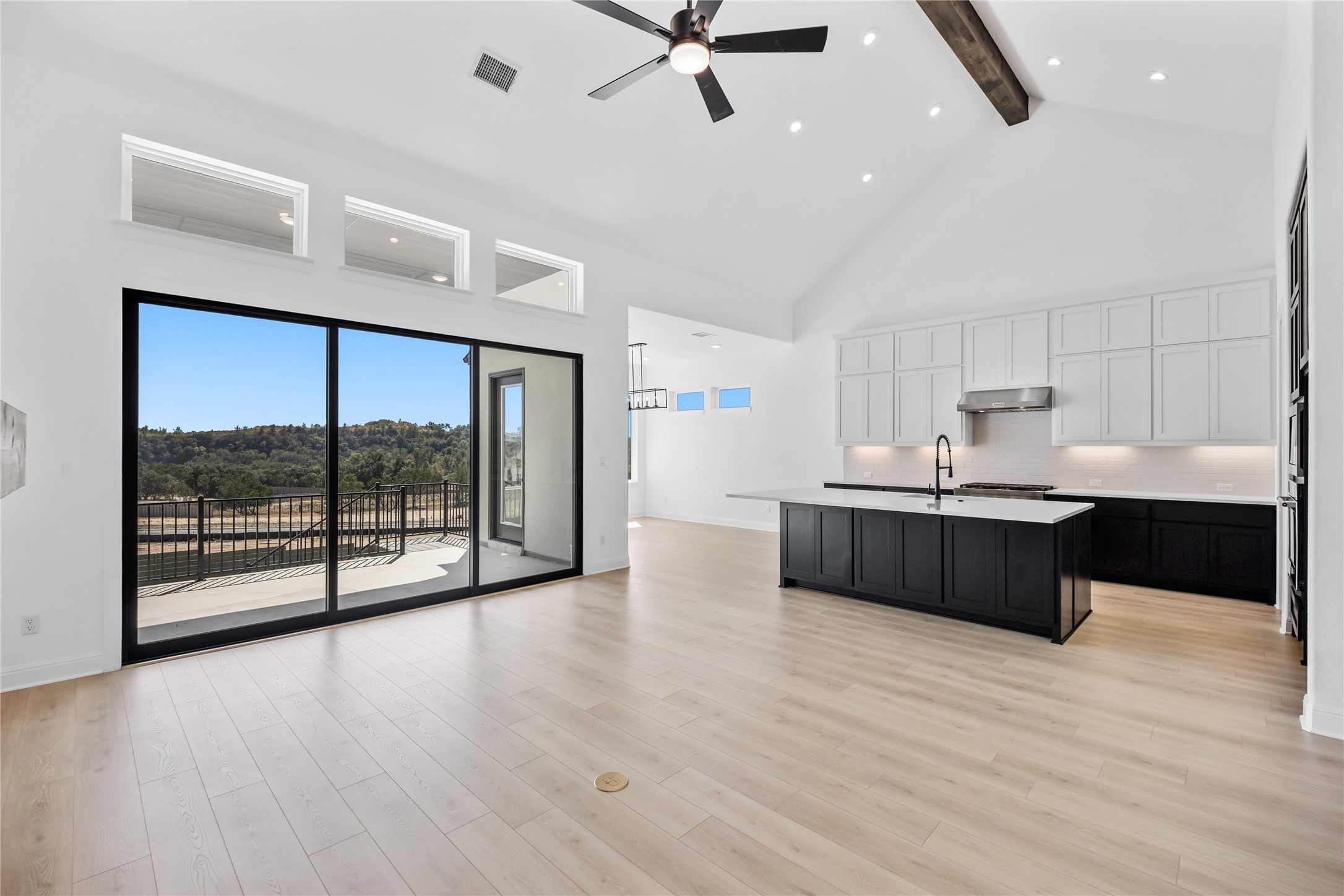3213 Lookout Mountain Road Georgetown, TX 78628 - Photo 40 of 40 Two tone kitchen featuring ceiling fan, dual tone cabinets, a center island with sink, open floor plan, and backsplash