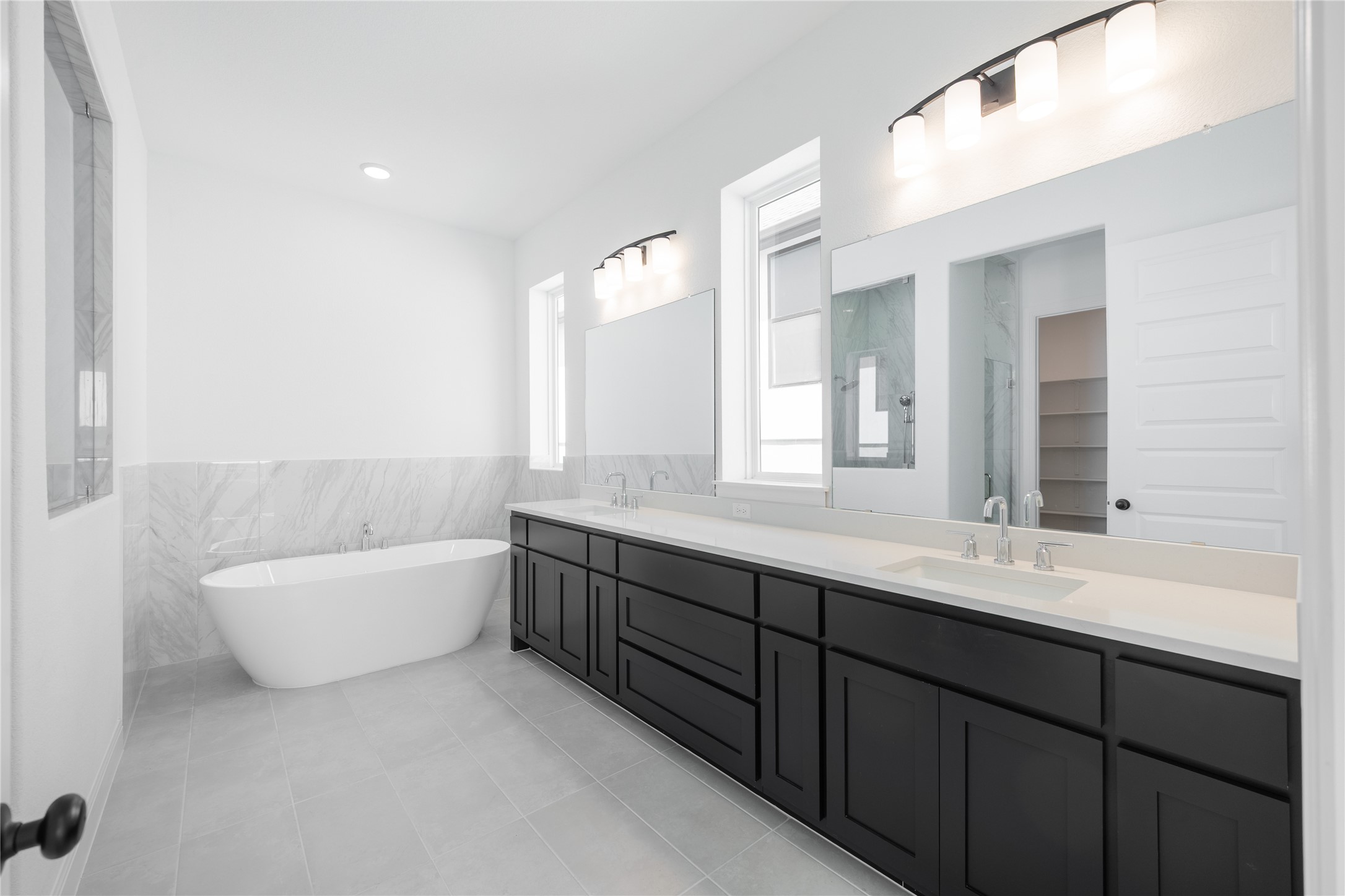 3213 Lookout Mountain Road Georgetown, TX 78628 - Photo 14 of 40 Primary Full bathroom featuring double vanity, a wainscoted wall, a freestanding tub, tile walls, and light tile patterned floors