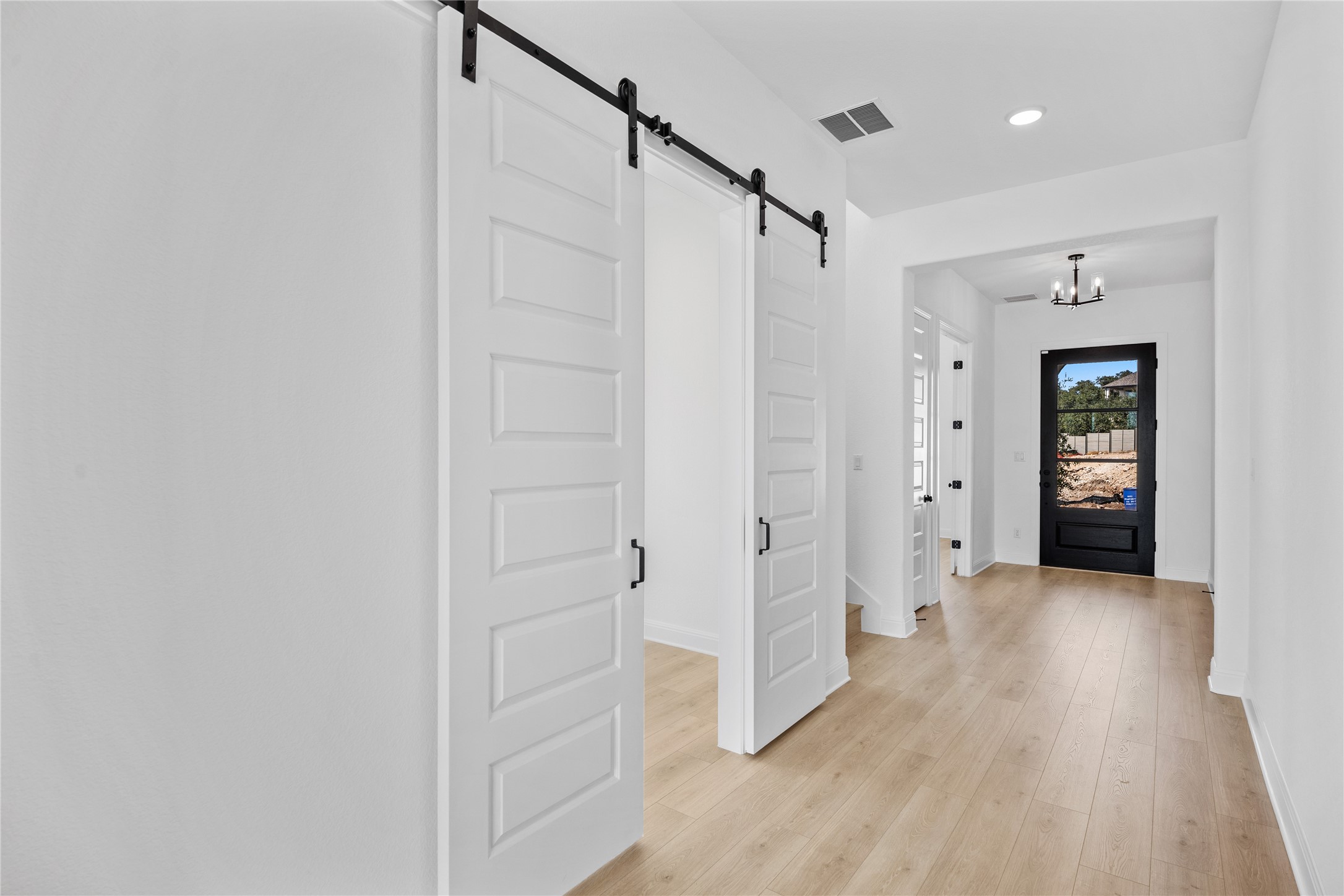 3213 Lookout Mountain Road Georgetown, TX 78628 - Photo 17 of 40 Hall with a barn door, light wood finished floors, and hanging lights