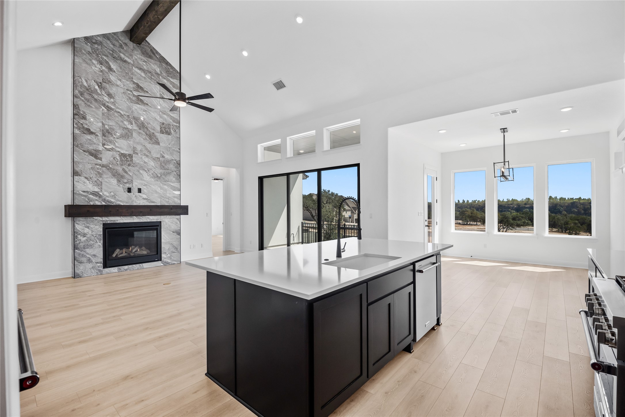 3213 Lookout Mountain Road Georgetown, TX 78628 - Photo 38 of 40 Kitchen with dark cabinetry, open floor plan, a fireplace, light wood-style floors, and a kitchen island with sink