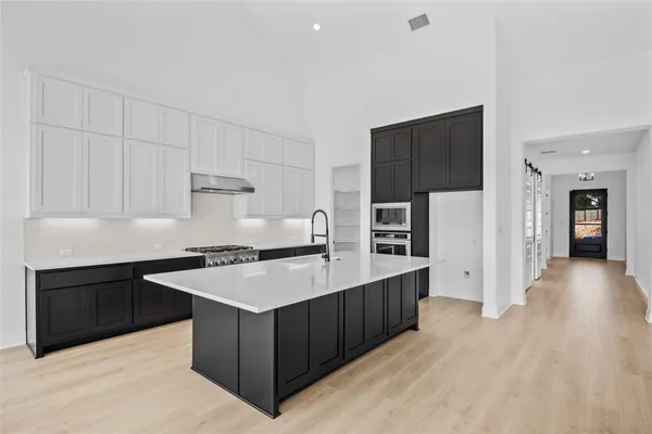 a large white kitchen with a large island oven