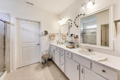 a bathroom with a double vanity sink mirror and shower