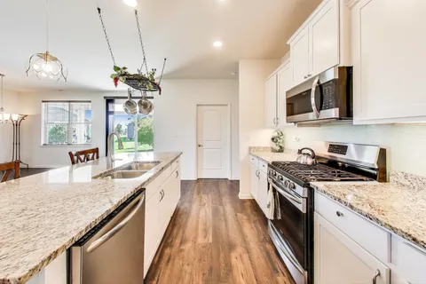 a large kitchen with stainless steel appliances granite countertop a stove a sink and a microwave