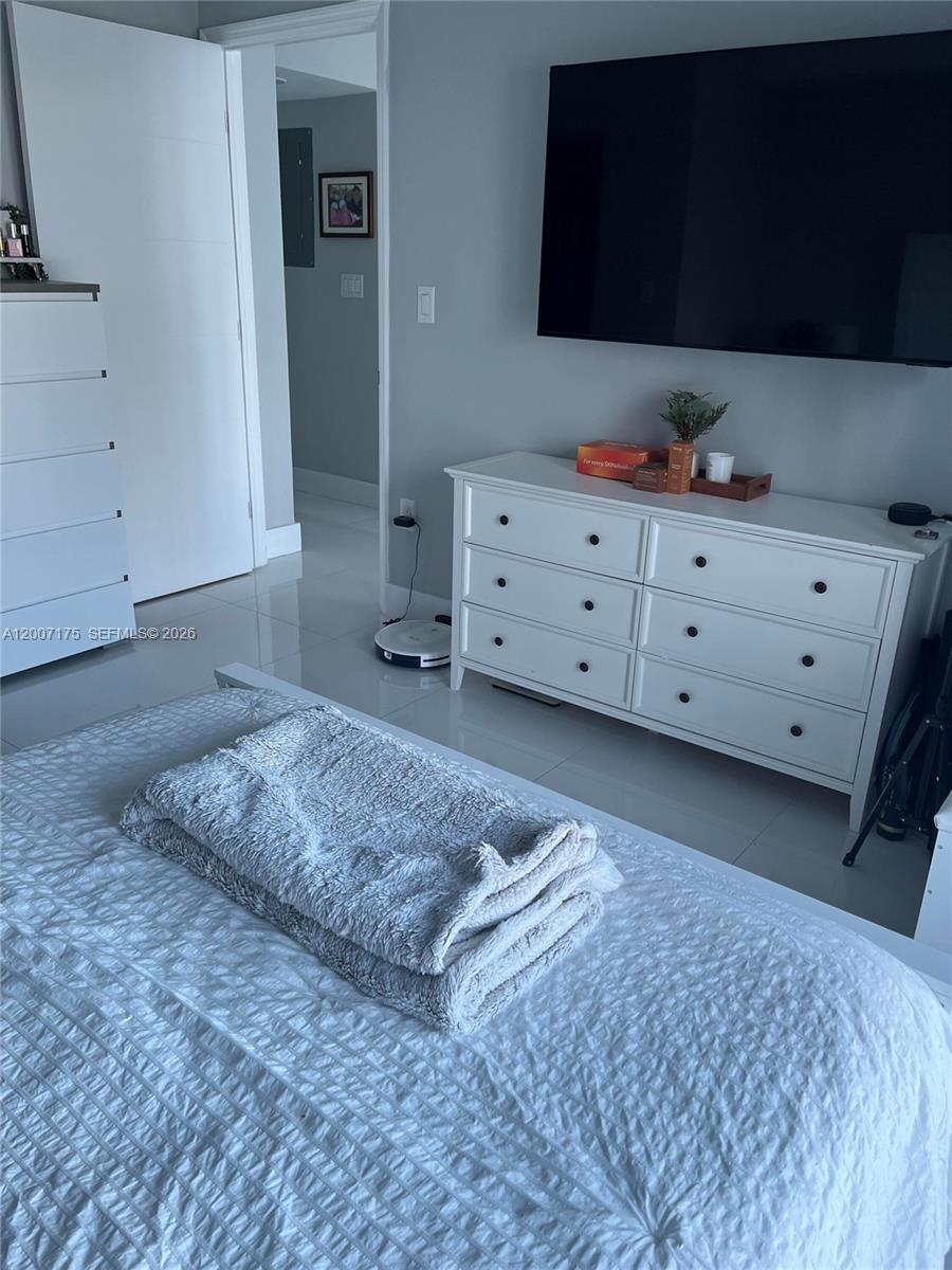 540 Brickell Key Drive, Unit 1809 Miami, FL 33131 - Photo 18 of 25 a bedroom with a bed and a flat tv screen on dresser