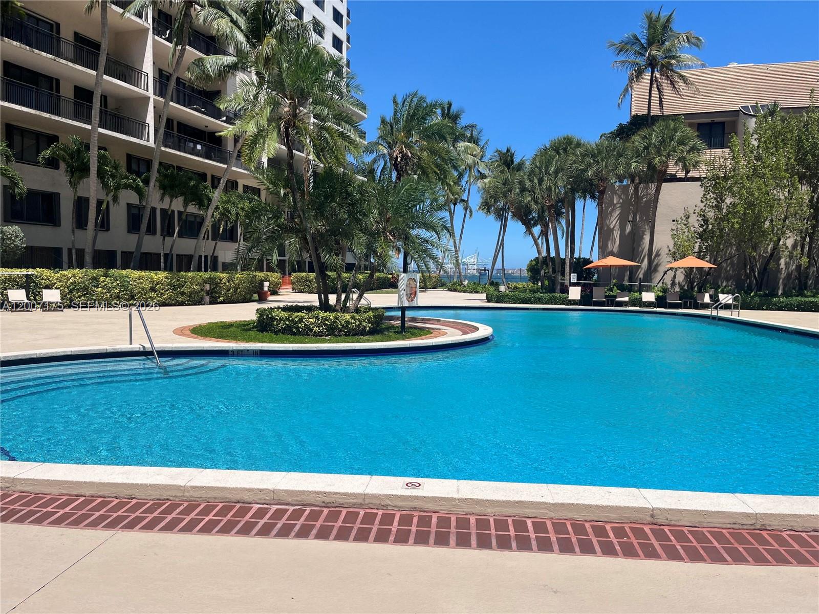 540 Brickell Key Drive, Unit 1809 Miami, FL 33131 - Photo 23 of 25 a view of a swimming pool with a yard and palm trees