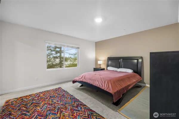 a bedroom with a bed and a lamp on dresser