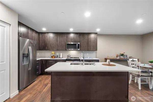 a kitchen with refrigerator a sink cabinets and wooden floor