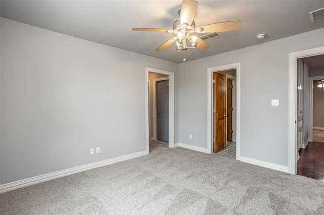 a view of an empty room with a chandelier fan