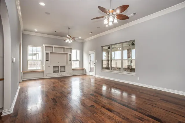a view of an empty room with a window and wooden floor