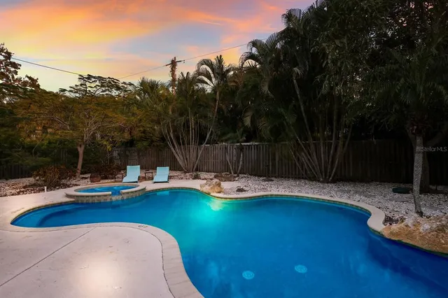 a view of a swimming pool with lounge chair and trees in the background