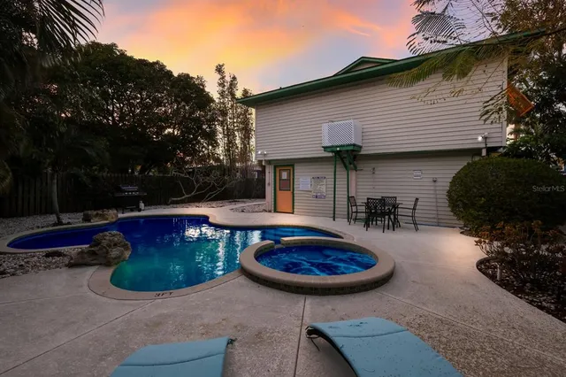a view of a backyard with table and chairs with plants and wooden fence