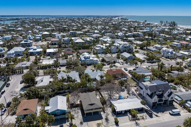 an aerial view of a city with lots of residential buildings and ocean view in back