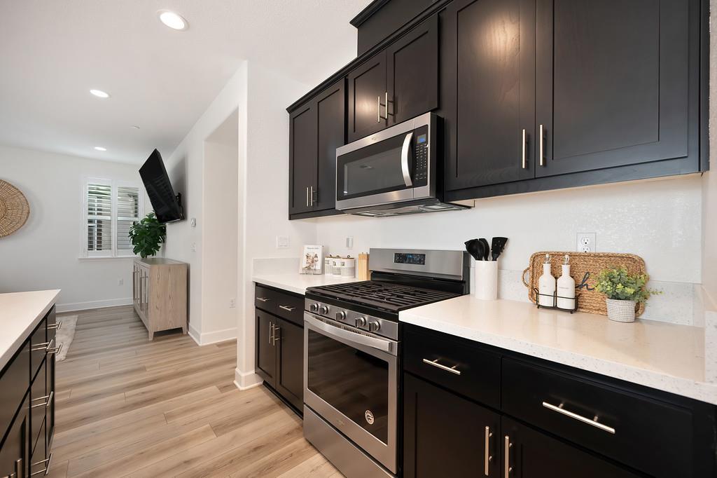 17500 Beachwood Road Lathrop, CA 95330 - Photo 24 of 78 a kitchen with stainless steel appliances a sink dishwasher a stove a microwave oven with wooden floor and cabinets