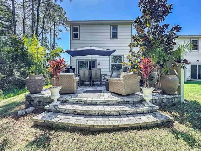 a view of a patio with couches plants and large trees