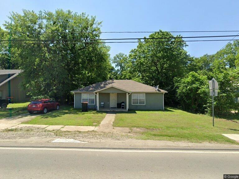 a white house with a large yard plants and large trees