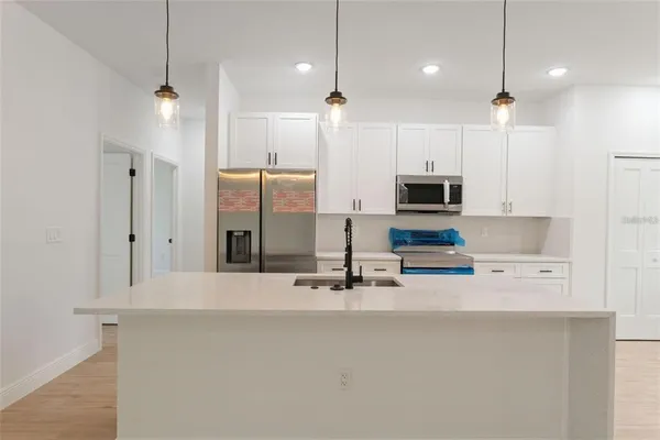 a kitchen with a sink a counter top space stainless steel appliances a window and cabinets