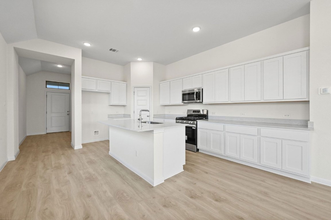 270 Bendecido Loop Elgin, TX 78621 - Photo 7 of 39 a kitchen with white cabinets and white appliances